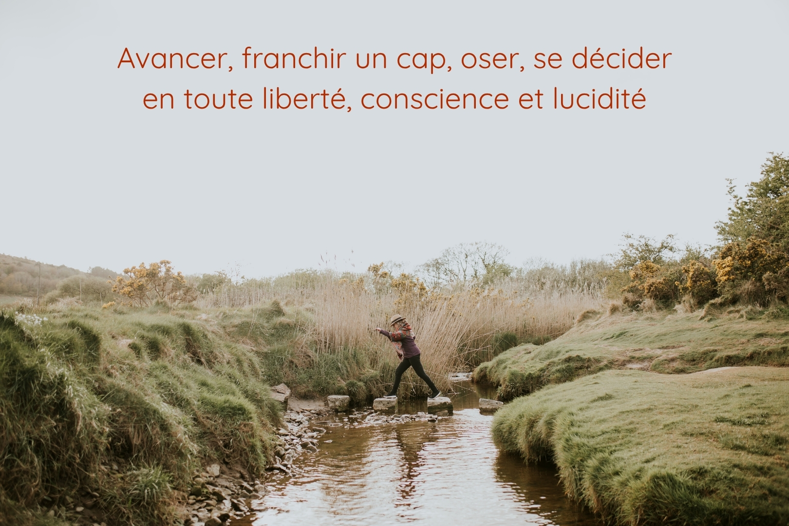 Une personne traverse une rivière en sautant de pierre en pierre, dans un paysage naturel et apaisant